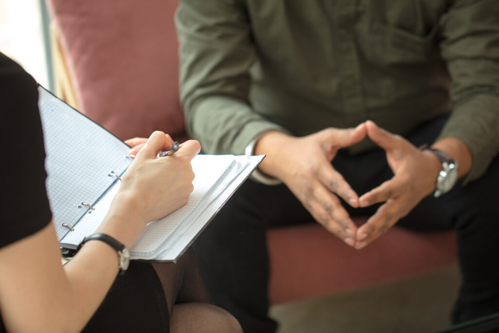 therapist writing down notes during therapy with her male patient