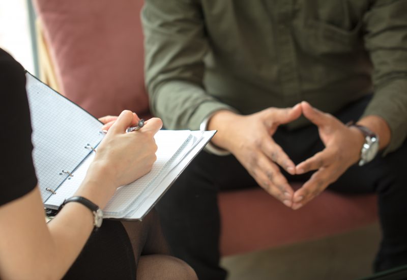 therapist writing down notes during therapy with her male patient